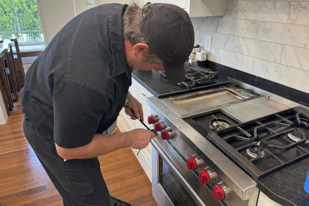 Technician servicing a stainless Wolf range in a Sands Point kitchen