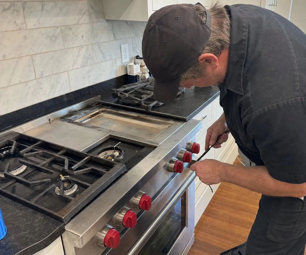 Technician servicing a stainless Wolf range up close
